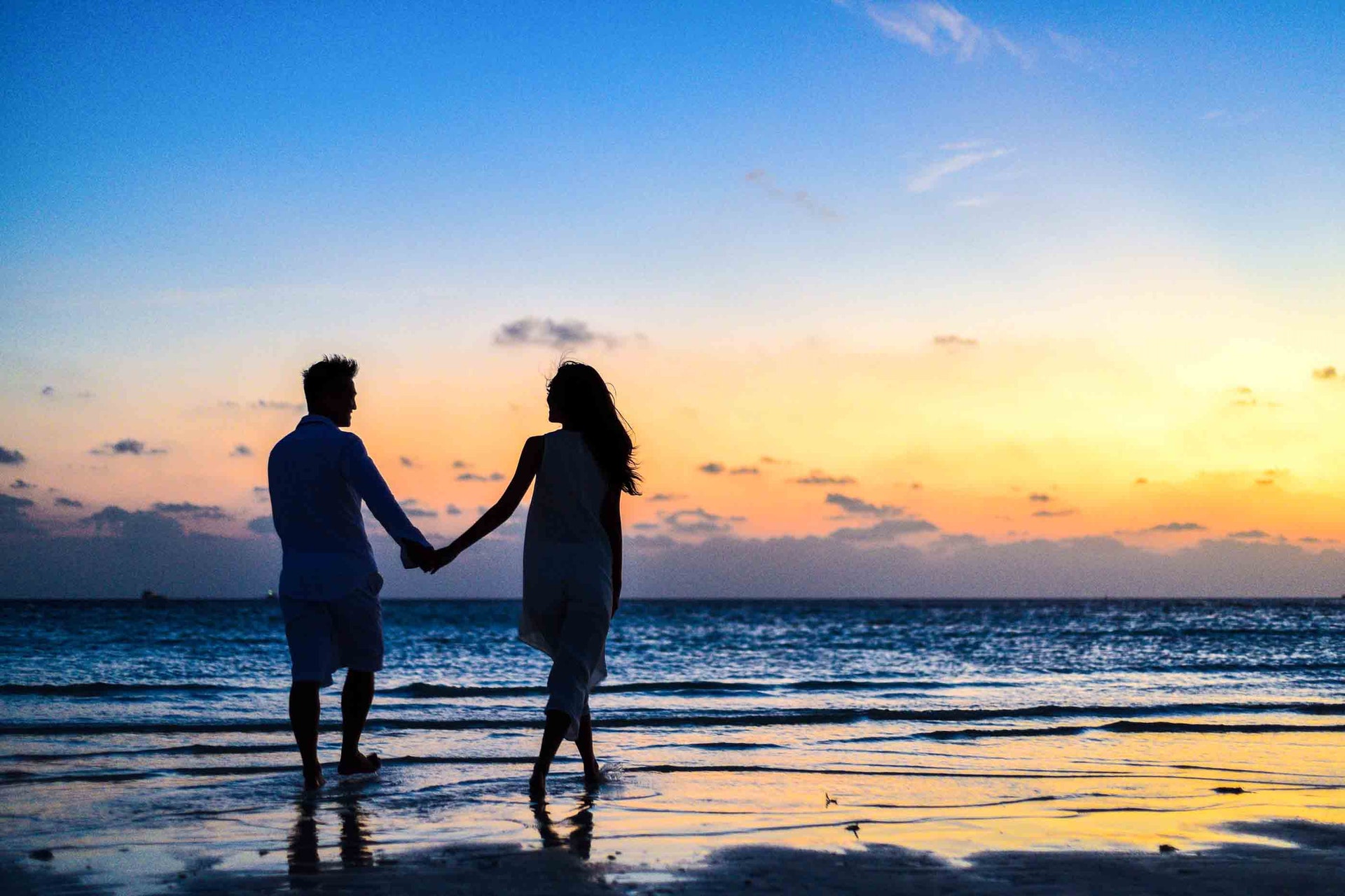 couple qui marche au bord de la mer en se tenant la main